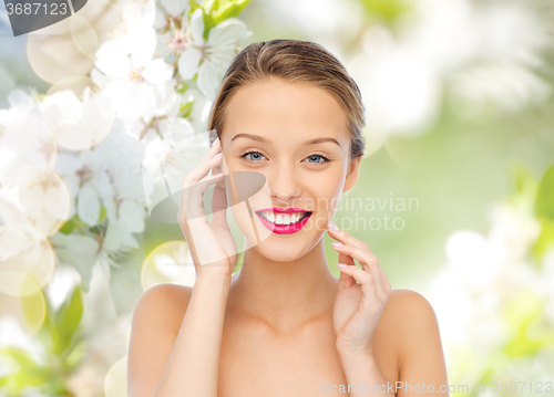 Image of smiling young woman with pink lipstick on lips