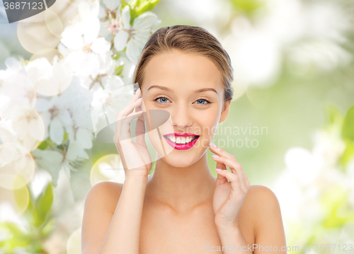 Image of smiling young woman with pink lipstick on lips