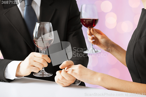 Image of hands of couple with diamond ring and wine glasses