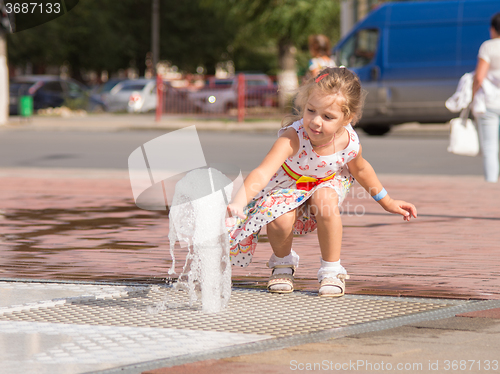 Image of  The child touched his hand to the jet fountain gushing from the earth