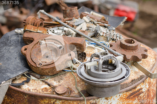 Image of  A pile of old broken pieces of iron lying on a rusty barrel