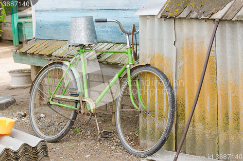 Image of Old bicycle with a bucket on the saddle
