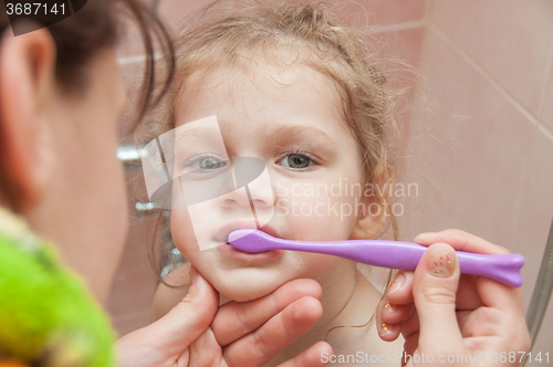 Image of Mom helping girl brushing teeth