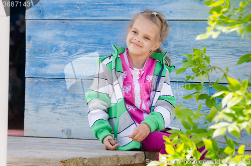 Image of Happy girl sitting on the porch in the village