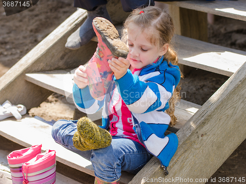 Image of Girl wears boots sitting on the porch in the village