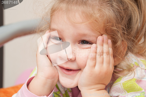 Image of The three-year girl interested looking at the left hand propping cheek