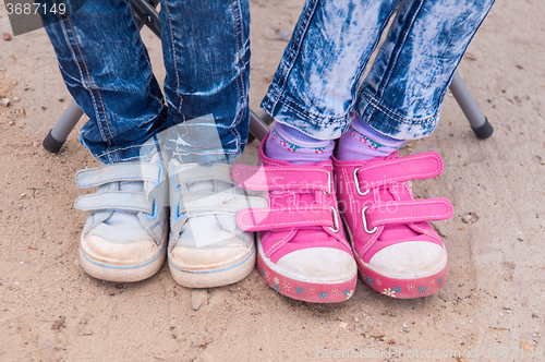 Image of Close-up of two pairs of children\'s feet dressed in jeans and sneakers