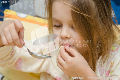 Image of Funny five year old girl eating spaghetti sitting in the crib