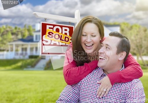 Image of Couple In Front of Sold For Sale Sign and House