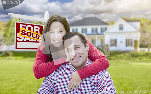 Image of Couple In Front of Sold For Sale Sign and House