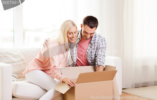 Image of happy couple with cardboard box or parcel at home