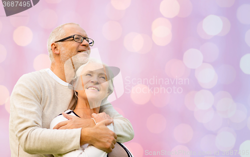 Image of happy senior couple hugging over lights background