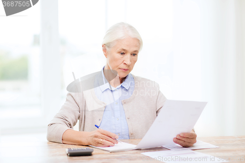 Image of senior woman with papers and calculator at home