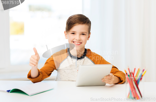Image of happy boy with tablet pc showing thumbs up at home