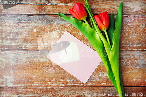 Image of close up of tulips and greeting card with heart