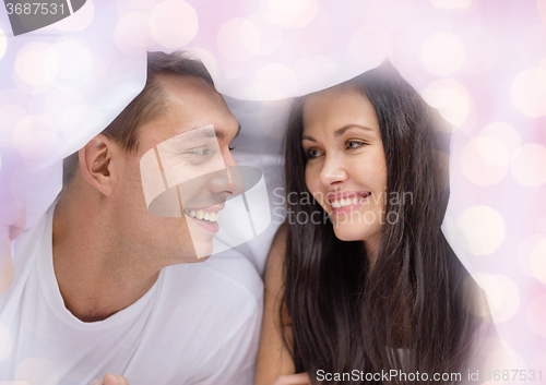 Image of happy couple under blanket in bed