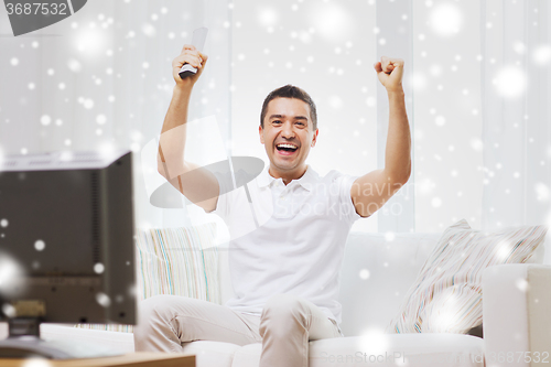 Image of smiling man watching sports at home