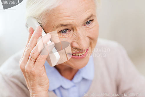 Image of senior woman with smartphone calling at home