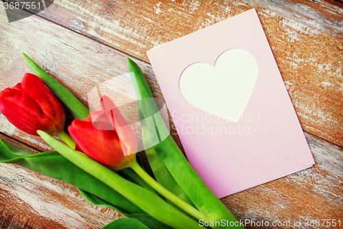 Image of close up of tulips and greeting card with heart