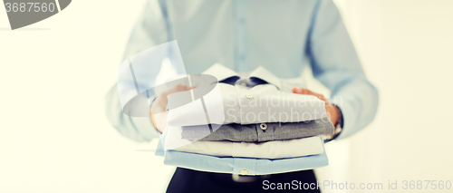 Image of close up of businessman holding folded shirts