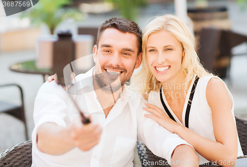 Image of happy couple taking selfie with smartphone at cafe