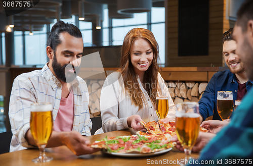 Image of friends eating pizza with beer at restaurant