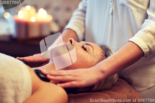 Image of close up of woman having hot stone massage in spa