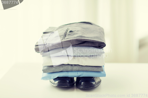 Image of close up of male shirts, pants and shoes on table