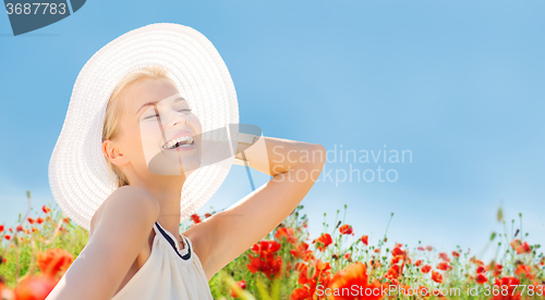 Image of smiling young woman in straw hat on poppy field