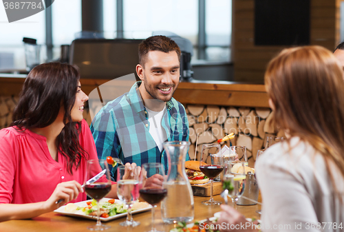 Image of happy friends having dinner at restaurant