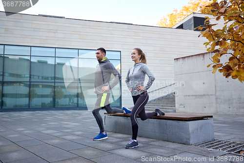 Image of happy man and woman exercising on bench outdoors