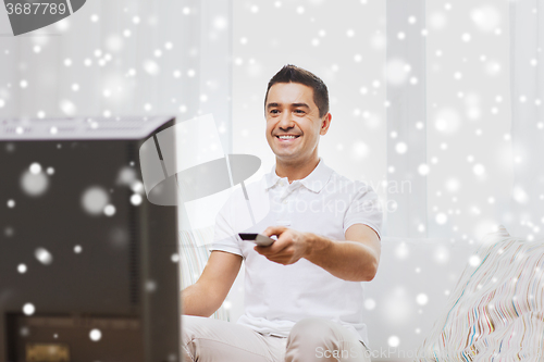 Image of smiling man with remote control watching tv