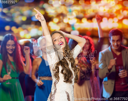 Image of happy young woman dancing at night club