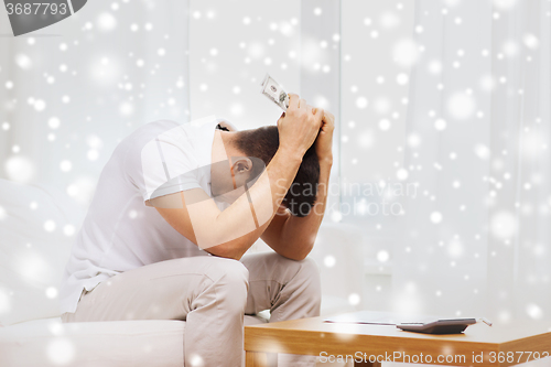 Image of man with money and calculator at home