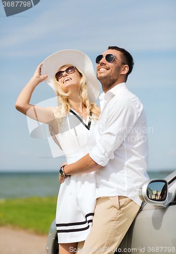 Image of happy man and woman hugging near car at sea