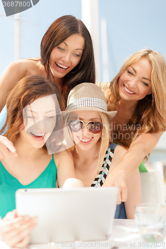 Image of smiling girls looking at tablet pc in cafe