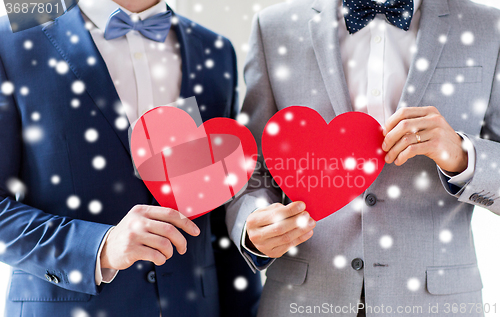 Image of close up of male gay couple holding red hearts