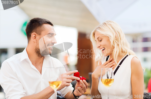 Image of happy couple with engagement ring and wine at cafe