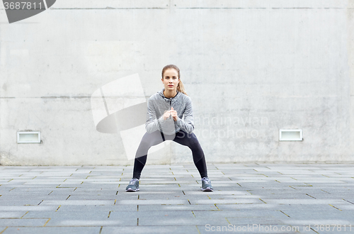 Image of woman doing squats and exercising outdoors