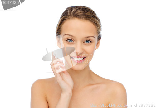 Image of happy young woman applying cream to her face