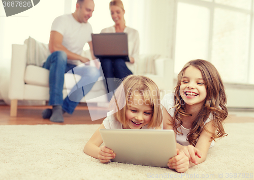 Image of smiling sister with tablet pc and parents on back