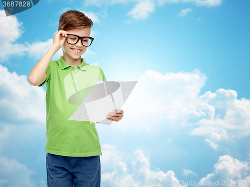 Image of happy boy in eyeglasses holding school test result