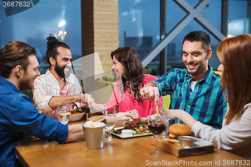 Image of friends eating and tasting food at restaurant