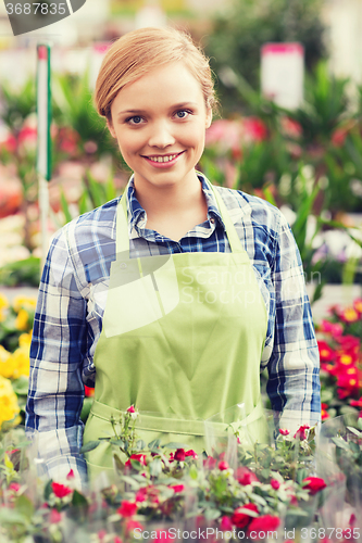 Image of happy woman with flowers in greenhouse