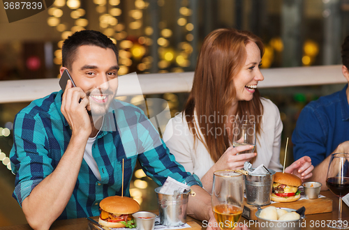 Image of man with smartphone and friends at restaurant