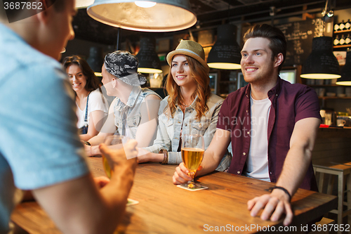 Image of happy friends drinking beer and talking at bar