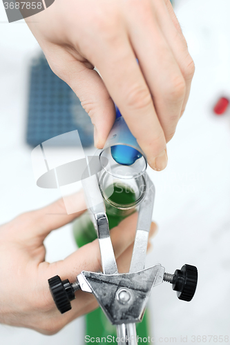 Image of close up of scientist filling test tubes in lab