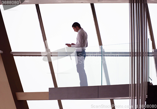 Image of young successful business man in penthouse apartment working on 