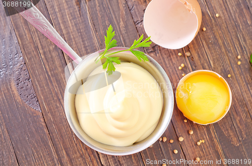 Image of mayonnaise in metal spoon on wooden board