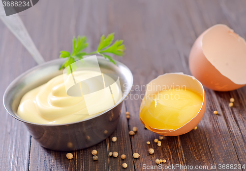 Image of mayonnaise in metal spoon on wooden board